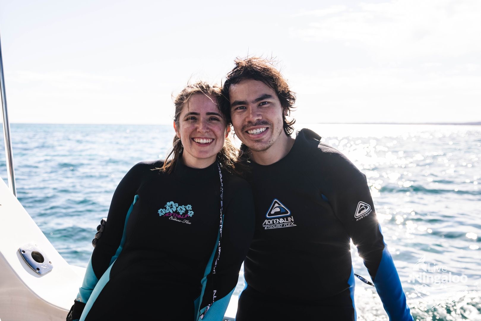 Sarah and Sam smiling together by the ocean